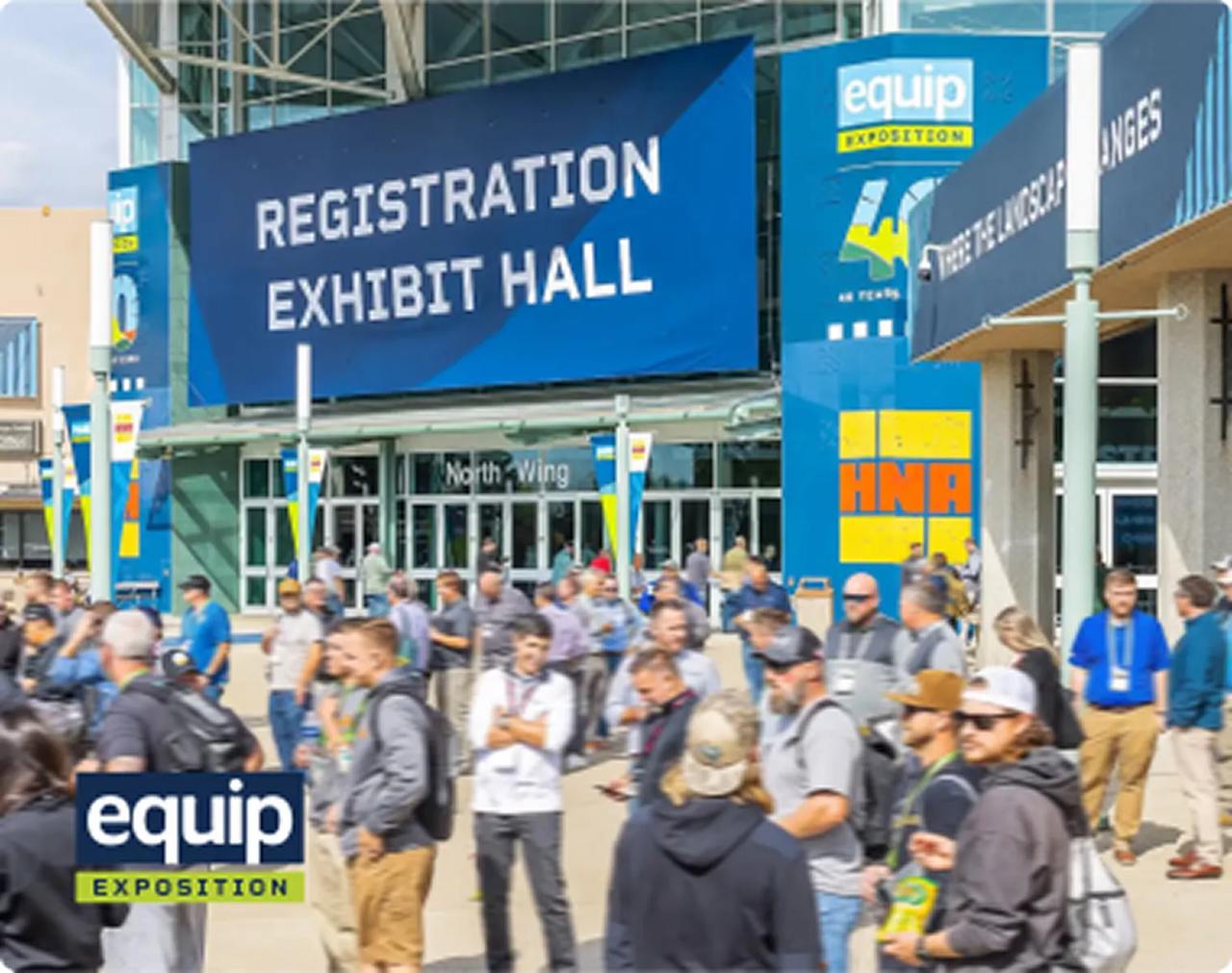 Crowd gathers outside Equip Exposition registration and exhibit hall under large blue banners and sunny skies.
