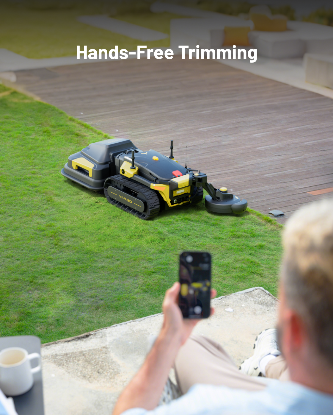 Black and yellow trimmer module by YARBO attached to robotic mower, shown in use on grass near patio, viewed from behind person using smartphone.