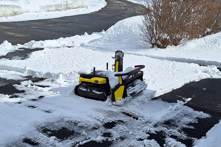 Yellow and black Yarbo snow blower clears icy slush from a snowy driveway, tackling tough winter conditions with power and precision.