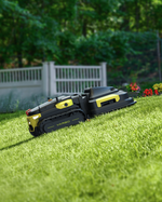 Black and yellow robotic lawn mower by Yarbo on green grass, side view with track wheels and compact design