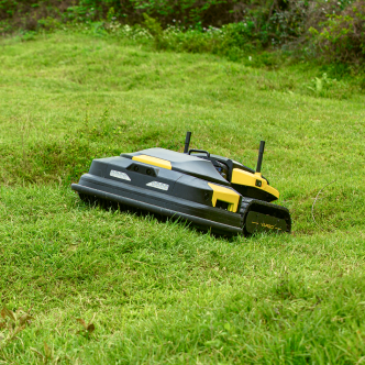 Black and yellow robotic lawn mower on green grass, featuring antennas and side brushes, in a sunny outdoor setting.