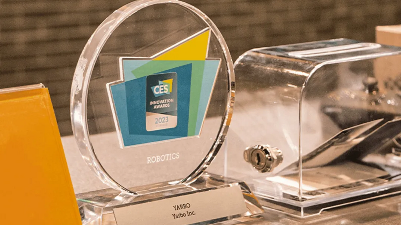 Clear circular CES 2023 Innovation Awards trophy for Robotics, engraved with "YARBO Yarbo Inc." on base, displayed with metallic device beside.