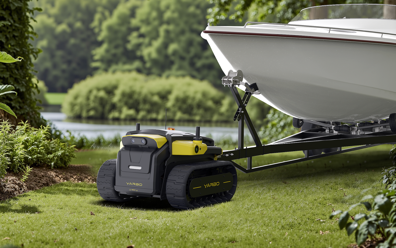 Yellow and black YARBO robotic lawn mower on grass near white boat on trailer, green trees and lake in background.