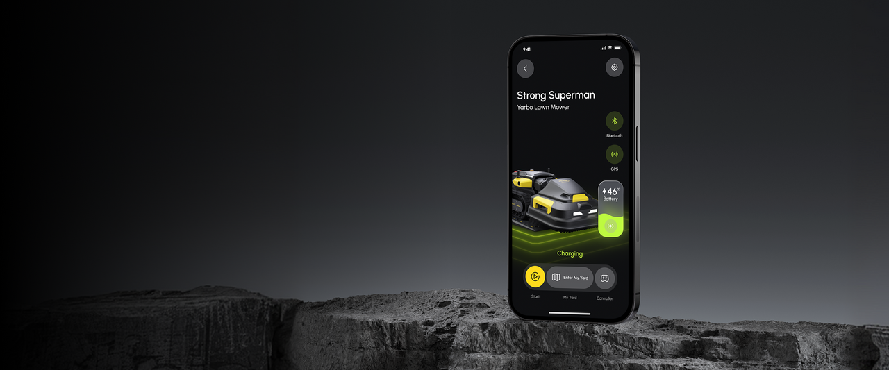 Smartphone displays Yarbo lawn mower app interface with charging status, 46% battery, and controls on dark rocky surface.