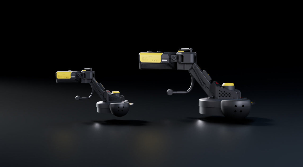 Two black and yellow robotic arms with articulated joints on dark reflective surface, studio lighting, no visible text.